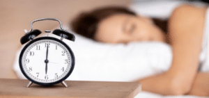 woman in bed by alarm clock