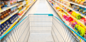 empty shopping cart going down full grocery aisle of processed food