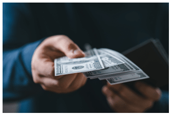 man in navy shirt handing large bills of cash