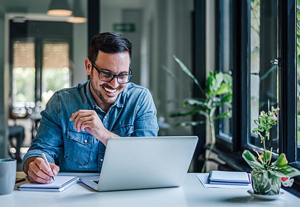 Happy Male Entrepreneur Writing Ideas On Note Pad. Businessman