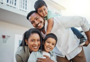 Portrait, happy family and piggyback outdoor at new home, real estate loan and building mortgage together. Parents, kids and smile outdoor for property investment, moving house and future security