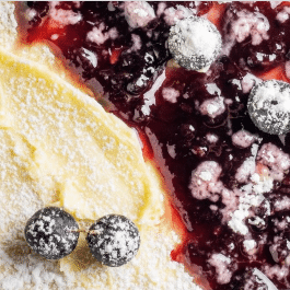 close up of a crepe with lemon cream and blueberry sauce on it