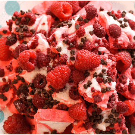 red and pink raspberry chocolate yogurt bark on a polka dot plate