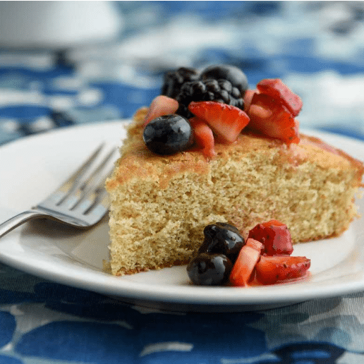 slice of sponge cake topped with cut strawberries, blueberries and blackberries