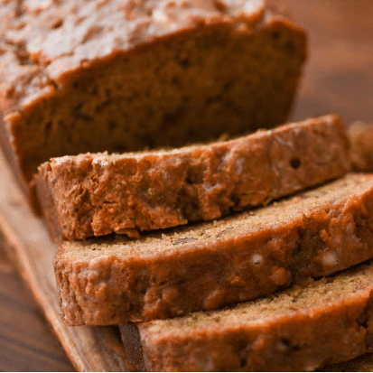 moist small load of brown bread cut on a wooden cutting board